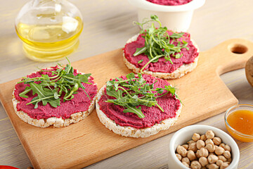 Rice crackers with tasty beet hummus and fresh sprouts on grey wooden background