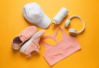 Sportswear, bottle of water and headphones on color background