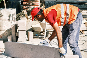 Pavement construction worker grabbing a big tile of pavement stone.