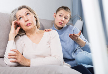 Portrait of offended senior woman turned away from her adult daughter
