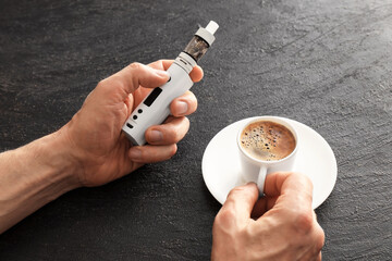 Man with vape mod and cup of coffee at table