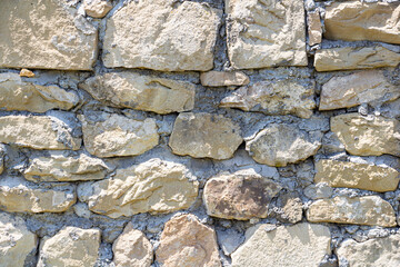The rough textured surface of the wild stone wall. Background.