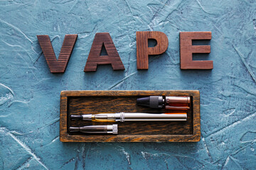 Electronic cigarette with word VAPE on color background