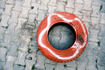 Old car tire painted in red for decorative purposes on the street
