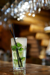 Mojito cocktail with straw on the bar. Close-up, selective focus.