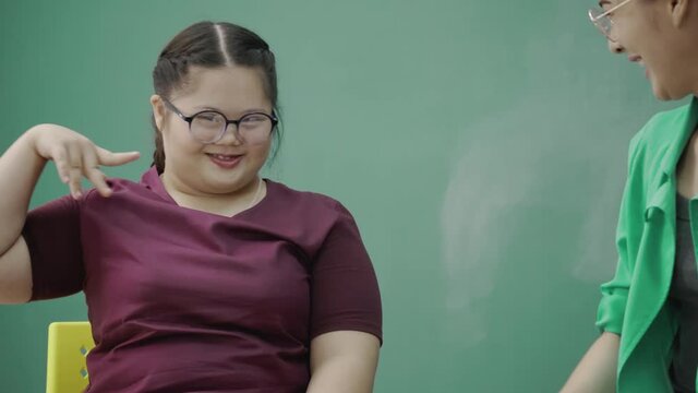 Autistic Asian girl sit in classroom with teacher and friend to do learning. young are happy doing activities to enhance knowledge skills. confidence to live together. Concept assertive