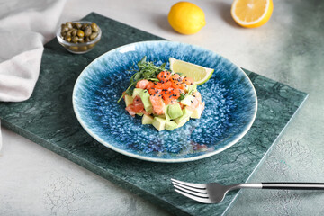 Delicious salmon tartar on grunge background