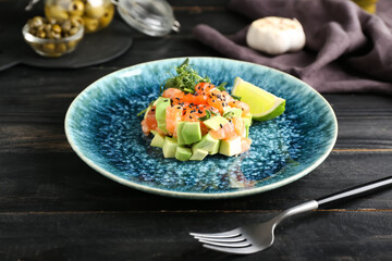 Delicious salmon tartar on dark wooden background