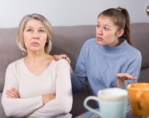 Portrait of offended senior woman turned away from her adult daughter