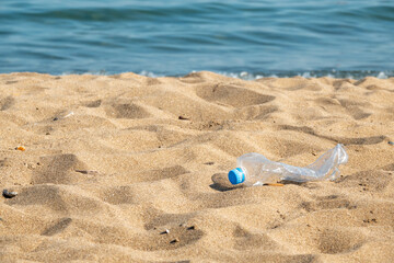 Plastic bottle is on the beach left by tourist