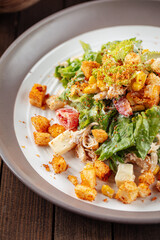 Russian malibu salad with croutons and ham on wooden background