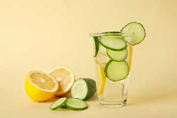 Glass with cucumber lemonade on color background
