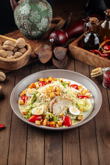 Plate of caesar salad with chicken and lettuce on wooden background