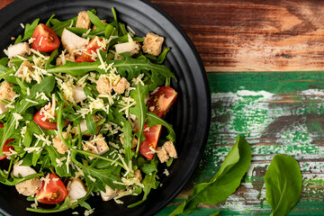 close up picture of fresh rocket salad with tomato, crouton, herb roasted chicken, and parmesan...