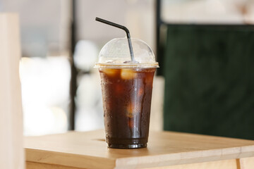 Plastic cup with tasty iced coffee on table