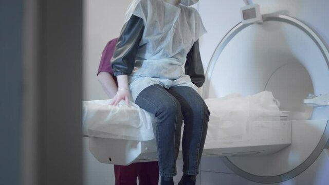 The doctor conducts an MRI or PET scan of a patient in a modern clinic. Girl on the bed inside a 3D scan machine. Magnetic resonance imaging in the study of the human body. The woman is doing CT scan