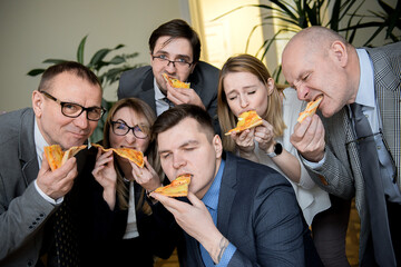 business, food, lunch and people concept - happy business team eating pizza in office