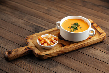 Lentil cream soup with dill and croutons on wooden background