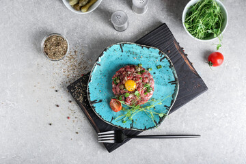 Plate with tasty beef tartare on grunge background