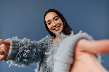 Happy fashionable cool girl with dark hair in fluffy blue clothes looking into camera and smiling on isolated background..