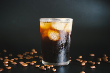 glass of iced americano coffee on black background with coffee beans 