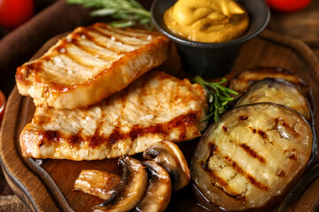 Board with tasty grilled vegetables and steaks on wooden background