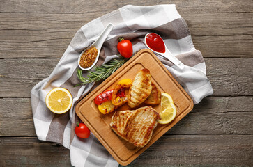 Board with tasty grilled pepper, bread and steaks on wooden background