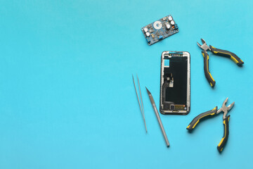 Disassembled mobile phone with technician tools on color background
