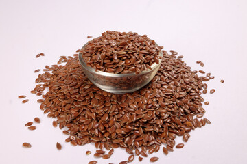 Flex seed flaxseed in small glass bowl over pile on white background