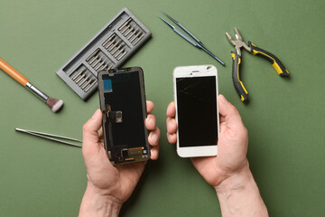 Male technician with disassembled mobile phone and technician tools on color background
