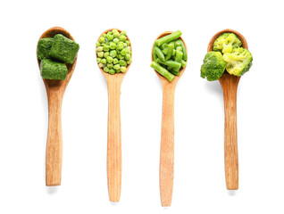 Spoons with frozen green vegetables on white background