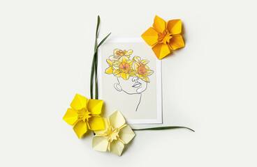 Origami narcissus flowers and greeting card on white background