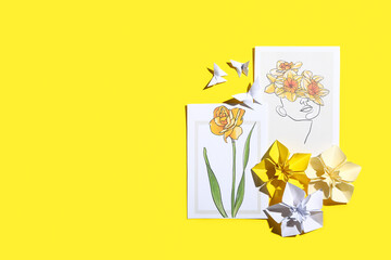Origami narcissus flowers and greeting cards on color background