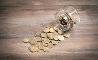 Jar of coins on wooden background.