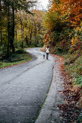 Fototapeta premium A young girl and a Weimaraner shorthaired dog walking along a mountain road
