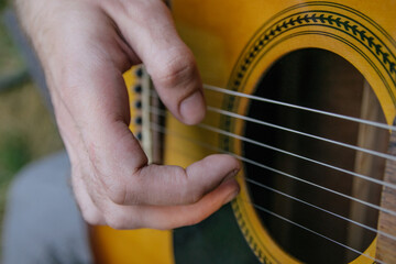 Fototapeta premium male hand playing guitar strings close up in nature