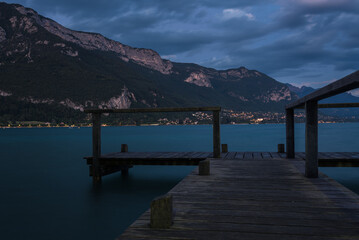 Small wooden dock with stunning view of the mountains above the water of annecy lake at sunset, Annecy, France