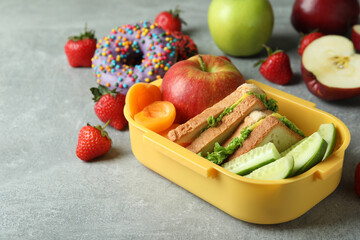 Lunch box with tasty food on gray textured background