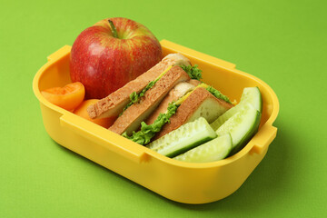 Lunch box with tasty food on green background
