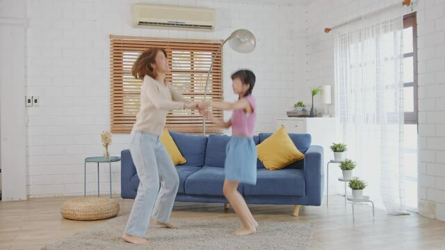 Happy Asian family mother and child daughter dancing at home.