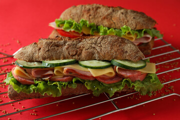 Baking rack with ciabatta sandwiches on red background