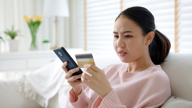 Upset Young Asia Teen Girl Sit At Home Sofa Couch Feel Shock Broke Doubt Annoy Or Lost Money In E-commerce App Error Buy Issue, Wrong Hoax Digital Wallet Hacked Or Bad Theft Steal Crime Fraud Banking.