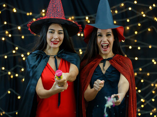 Obraz premium Cheerful girlfriends with serpentine crackers celebrating Halloween