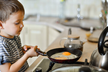 a four-year-old boy in the kitchen is preparing breakfast, a boy is preparing scrambled eggs