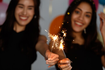 Two young and beautiful sexy Asian girls in a black dress playing with small little fireworks with fun and happiness in celebrating party