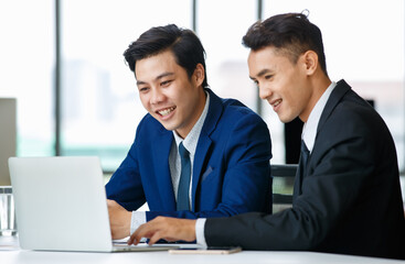 Content male colleagues working on laptop in office