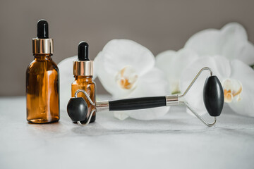 Body and skin care products, dropper bottles and obsidian stone guasha massage roller in the...