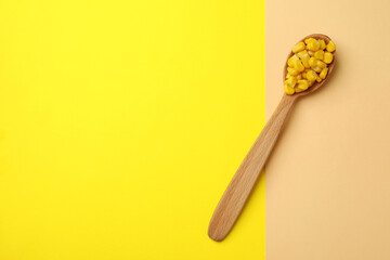Spoon with corn seeds on two tone background