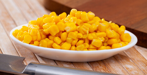Cooked sweet corn kernels in bowl on wooden table