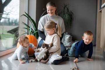 mother with her three children playing with a cat on the floor at home